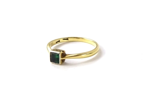 An Art Deco style emerald set dress ring, with square cut emerald, in rub over platinum setting, with etched design raised borders, on plain shoulders and yellow metal band, ring size Q, 2.7g all in.