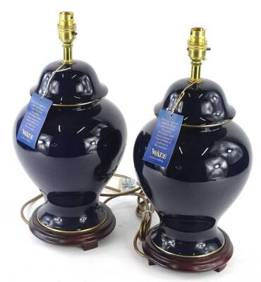 A pair of Wade ceramic table lamps, each with a deep blue glaze and hardwood stand, original labels and unused, 43cm H.