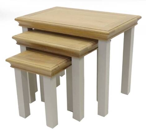 A nest of three ex shop display Edinburgh oak and cream painted tables, 66cm W.