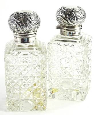 A pair of George V silver scent bottles, each with an embossed silver lid and cut glass base, Birmingham 1924, 12cm H.