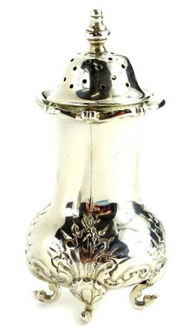 An Edwardian silver pepper pot, the base decorated with scrolls, shells, etc., on four shaped feet, London 1906, 1½oz.