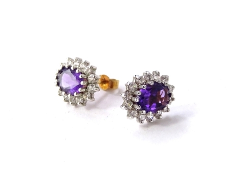 A pair of 9ct gold amethyst and CZ earrings, beach in floral cluster design, set with border of white stones and central oval cut amethyst, with butterfly backs, 1cm high, 2.6g all in.