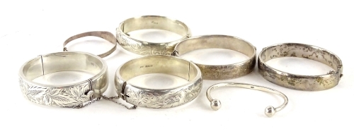 Seven silver bangles, to include four Victorian hinged bangles, (AF), a child's silver bangle, a child's silver talk bangle, and a later silver etched design hinged bangle, 126.7g all in. (1 boxed)