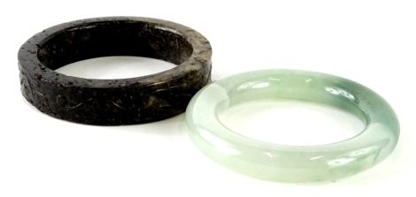 An oriental green hard stone bangle, and a carved soapstone bangle. (2)