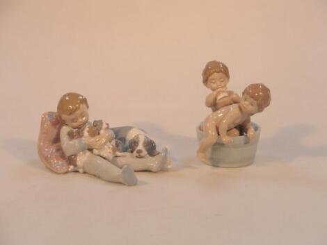 A Lladro figure group of a young child asleep with puppies and another