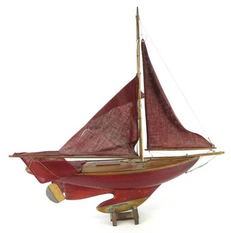 A maroon painted pond yacht, with single mast, makers plaque for A.W Gamage of London, 64cm L overall. (AF)