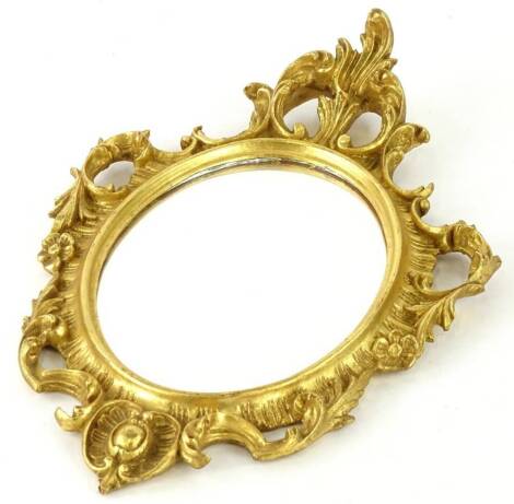 A gilt wood and gesso oval wall mirror, the frame with pierced foliate and rococo scrolls, 44cm x 29cm.