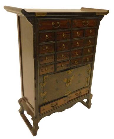 A Korean elm side cabinet, with a shaped top, above an arrangement of a small and larger drawers, each with inscriptions and two panel doors, with brass mounts, on shaped legs, 82cm H, 64cm W.