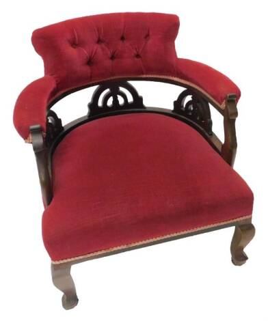 An Edwardian mahogany tub shaped chair, with buttoned upholstery in red fabric on cabriole legs with ceramic castors.