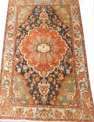 A Persian type rug, with a central medallion, on a red ground, surrounded by part green spandrels, one wide and two narrow borders.