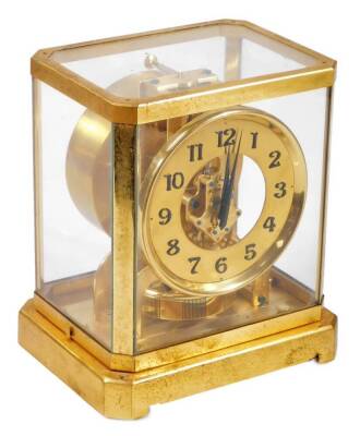 A Jaeger LeCoultre Atmos mantel clock, in a four part glazed case with gilt metal surround, 13cm Dia. Arabic dial, numbered 6604, on a canted base, with a visible movement and plain back plate, 24cm H, 20cm W, 16cm D.