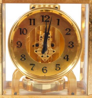 A Jaeger LeCoultre Atmos mantel clock, in a four part glazed case with gilt metal surround, 13cm Dia. Arabic dial, numbered 6604, on a canted base, with a visible movement and plain back plate, 24cm H, 20cm W, 16cm D. - 2