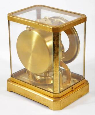 A Jaeger LeCoultre Atmos mantel clock, in a four part glazed case with gilt metal surround, 13cm Dia. Arabic dial, numbered 6604, on a canted base, with a visible movement and plain back plate, 24cm H, 20cm W, 16cm D. - 6