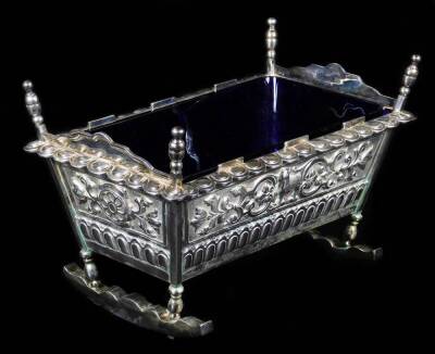 Withdrawn Pre-Sale by vendor A George V silver cradle, by Henry Wilkinson & Co, with bun cup and cover finials, lappet rim and cast and chased sides, raised with scrolls, ram and Tudor rose, with blue glass liner inscribed Arthur Stannage Whitehead Master