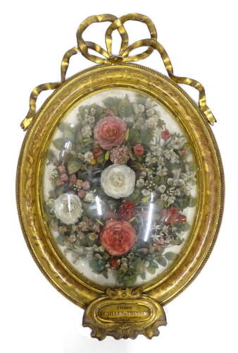 A mid 19thC French silk flower display, representing roses, leaves and other similar flowers, in oval gesso frame, the crest decorated with a bow, etc., exhibition plaque titled Fleurs, ACAILLES de POISSONS, brevet de l'exposition 1855, 61cm x 41cm.