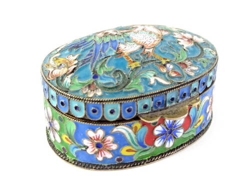 A Russian white metal and cloisonne enamel oval box, the hinged lid decorated with a bird, flanked by flowers, leaves, etc., the base with a band of brightly coloured flowers, stamped to the base 84, 5.5cm W.