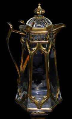 A Victorian crystal and silver-gilt Gothic framed claret jug, by Edward H Stockwell, with inverted finial, shaped spout, floral handle, and panelled body on hexagonal base, London 1873, 30cm H.