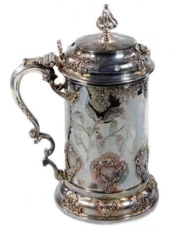 A William III and later silver ceremonial tankard, with design of a gadrooned flame finial, compressed domed lid, leafy capped thumb mould handle and applied and chased body, set with fern leaves and scrolls, on a shaped base set with satyr mask heads, in