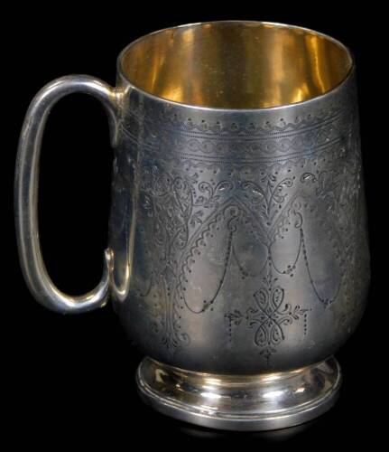 A Victorian silver christening mug, of bell shaped form with C scroll handle, on circular foot, the body partially chased with garlands, flowers and scrolls, London 1880, 9cm H, 4oz.