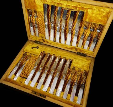 A set of Edwardian bright cut mother of pearl entree knives and forks, with silver collars, in fitted mahogany canteen, part settings for twelve, 31cm W.