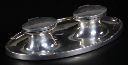 A George V silver double inkstand, of oval form, with two inkwells each with glass liners, Birmingham 1914, 17cm W, 8½oz all in. (weighted)