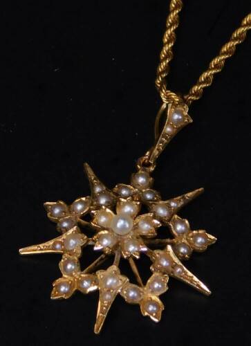 An Edwardian pendant brooch, of star form, set with small pearls, attached to an associated rope twist chain, marked 15, 43cm L, 8.5g all in, the pendant brooch unmarked. (2)