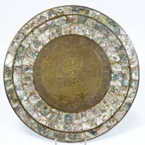 A 19thC Indo Portuguese dish, of circular form, with outer mother of pearl sections and inner metal centre, decorated and raised with a mask and various zodiac type signs, unmarked, 40cm Dia