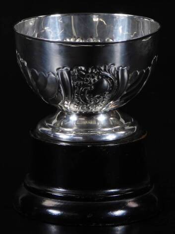 An Edwardian silver monteith bowl, of small proportion, the circular body repoussé decorated with scrolls and flowerheads, on a circular foot, Birmingham 1907, 8cm H, 2oz, on ebonised plinth base.