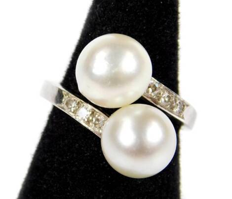 A cultured pearl and diamond twist ring, set with two silvered coloured cultured pearls, one to each twist, three diamonds to each shoulder, each round brilliant cut approx 0.5cts, on white metal band, unmarked but bears makers stamp P (thistle symbol) M,