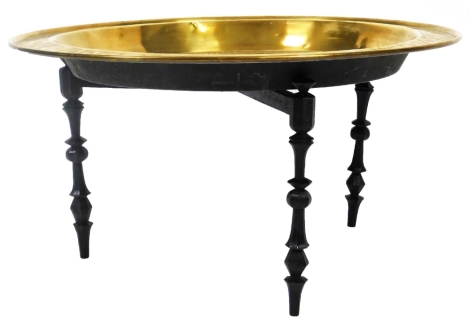 A Benares type brass tray top table, of circular form, with a deep well, decorated with a repeat geometric pattern, with an outer dot border, 72cm Dia. on a folding stand.