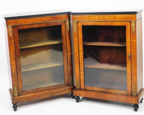 A near pair of Victorian walnut inlaid and ebonised pier cabinets, each of rectangular form, with a glazed door flanked by gilt metal corners, on a plinth base terminating in turned feet, 108cm H, 78cm W, 30cm D. (2)