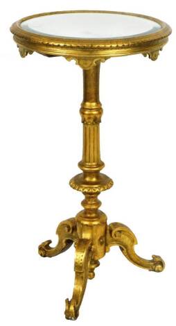 A gilt wood occasional tripod table, the circular bevel mirror top raised on a heavily carved stem terminating in triple scroll cabriole legs, 78cm H, 43cm Dia.