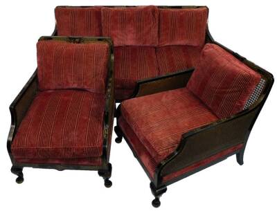 An early 20thC bergere Japanned and black lacquer three piece suite, comprising a three seater settee and two armchairs, with bergere sides, on squat cabriole legs with gilt highlights, decorated with flowers, geometric flowerheads, etc. each chair 86cm