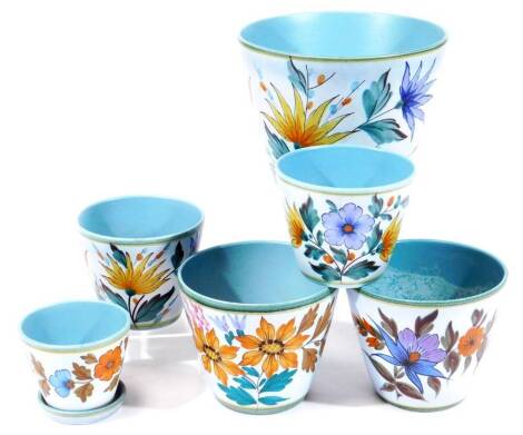 A pair of Gouda Flora plant pots, decorated with flowers on a matt blue ground, 13cm H, together with a small pair, 11cm H, a single large, 18cm H and a cache pot and stand, 9cm H. (7)