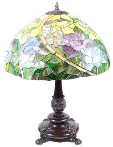 A Tiffany style table lamp, with large shade decorated with flowers, predominately in green, purple and blue, on a metal stand, the shade 47cm W.