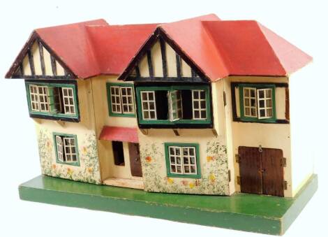 A 20thC wooden doll's house, mock Tudor style, with hinged front and two floors, on a rectangular base, polychrome decorated predominately in red, black and green, 43cm H, 68cm W, 27cm D.