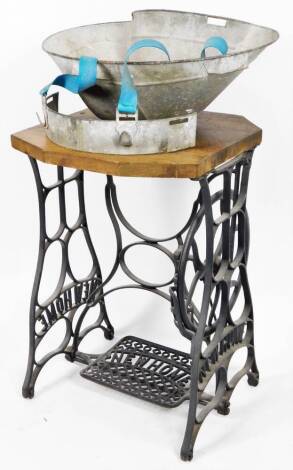 A cast iron and wooden sewing machine treadle stand, marked Newhome, with adjustable foot pedal, on shaped stiles, 75cm H, 53cm W, 51cm D and a zinc galvanized seed spreader.