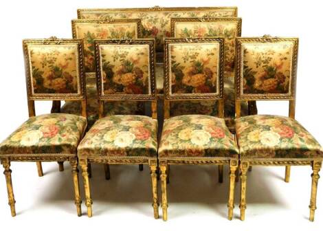 A 19thC French gilt wood salon suite, comprising three seater sofa, two carver chairs and four chairs, each in floral material, with gilt wood surrounds, surmounted by scrolls and berries, the settee 98cm H, 150cm W, 52cm D. (5)