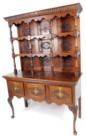 A 20thC oak dresser, the upper section with open delft racks, separated by baluster columns, the sub section set with three panelled deep drawers, on cabriole front legs terminating in pad feet, 193cm H, 136cm W, 50cm D.