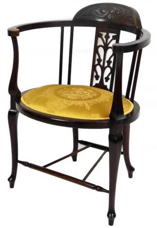 An Edwardian mahogany occasional chair, with carved cresting rail, C scroll arms, overstuffed seat and cabriole front legs joined by turned stretchers, 76cm H.