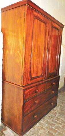 A George III mahogany linen press, with fielded panel doors raised above a sub section of two short and two long drawers, with a part fitted interior, 198cm H, 125cm W, 61cm D.