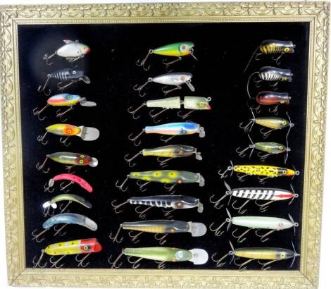 A cased set of pike fishing lure, of varying forms and colours, 12cm W, etc. (a quantity, framed)