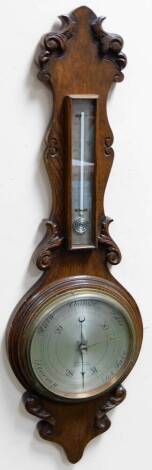 E H Penn. Shepton Mallet. An early 20thC oak barometer and thermometer in carved case, the rectangular thermometer raised above a 19cm Dia. silvered dial, signed, with Arabic numerals, 88cm H.