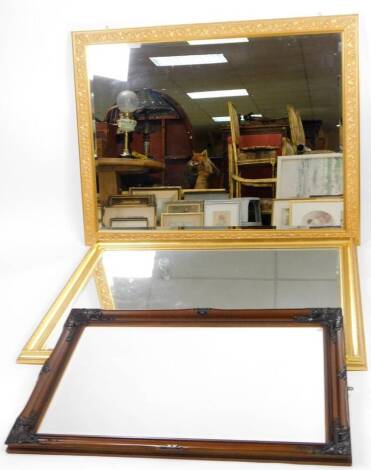 A rectangular mirror, in gilt coloured frame with bevel glass and raised leaf and floral border, 139cm x 104cm, and two other mirrors of large proportion. (3)