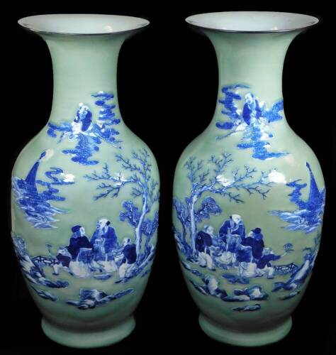 A pair of 19thC Chinese porcelain celadon vases, each of shouldered form, with trumpet stems, the bodies raised with figures of scholars, children, trees, buildings, etc. on a green ground, on circular foot, unmarked, 56cm H. (2) (AF)