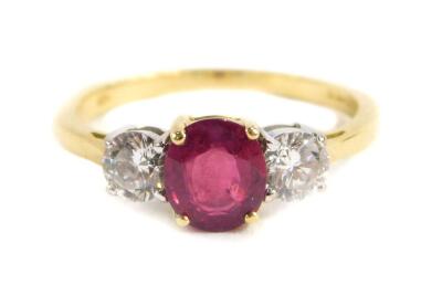 An 18ct gold ruby and diamond three stone ring, central set with oval cut ruby approx 6.62mm x 5.80mm x 2.95mm depth, total estimated carat weight 1ct, in a gold four claw setting, flanked by two round brilliant cut diamonds, each measuring 4.10mm x 4.2mm
