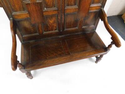 A 19thC oak settle, with a panelled back, scrolling arms and solid seat, raised on turned legs united by stretchers, 115cm H, 125cm W. - 3