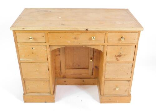 A pine kneehole desk, with a central drawer above a cupboard flanked by eight graduated small drawers, raised on a plinth base, 80cm H, 103cm W, 50cm D.