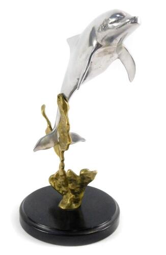 An aluminium and brass sculpture of a dolphin, modelled on sea weed, on a circular base, 25cm H.