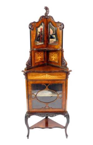 A Victorian rosewood and inlaid corner display cabinet, the top with rococo leaf carving, two shaped bevelled mirrors, and two panels inlaid with classical urns, and a single shaped shelf, over glazed door enclosing a single shelf, raised on leaf carved c